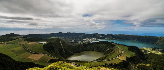 A panoramic view from a mountain peak, showcasing the vast ocean stretching to the horizon under a clear blue sky.