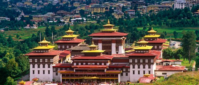 A serene Buddhist temple in Bhutan, featuring intricate architecture and surrounded by lush green mountains.