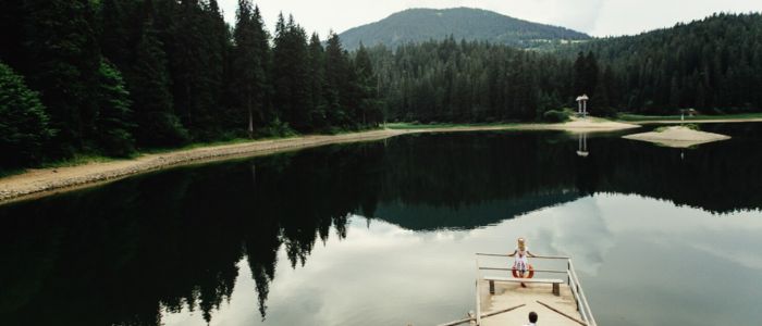 A boat is docked on a serene lake, with a majestic mountain rising in the background.