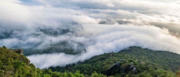 A panoramic view of fluffy clouds stretching across the sky from a mountain summit, showcasing nature's beauty.