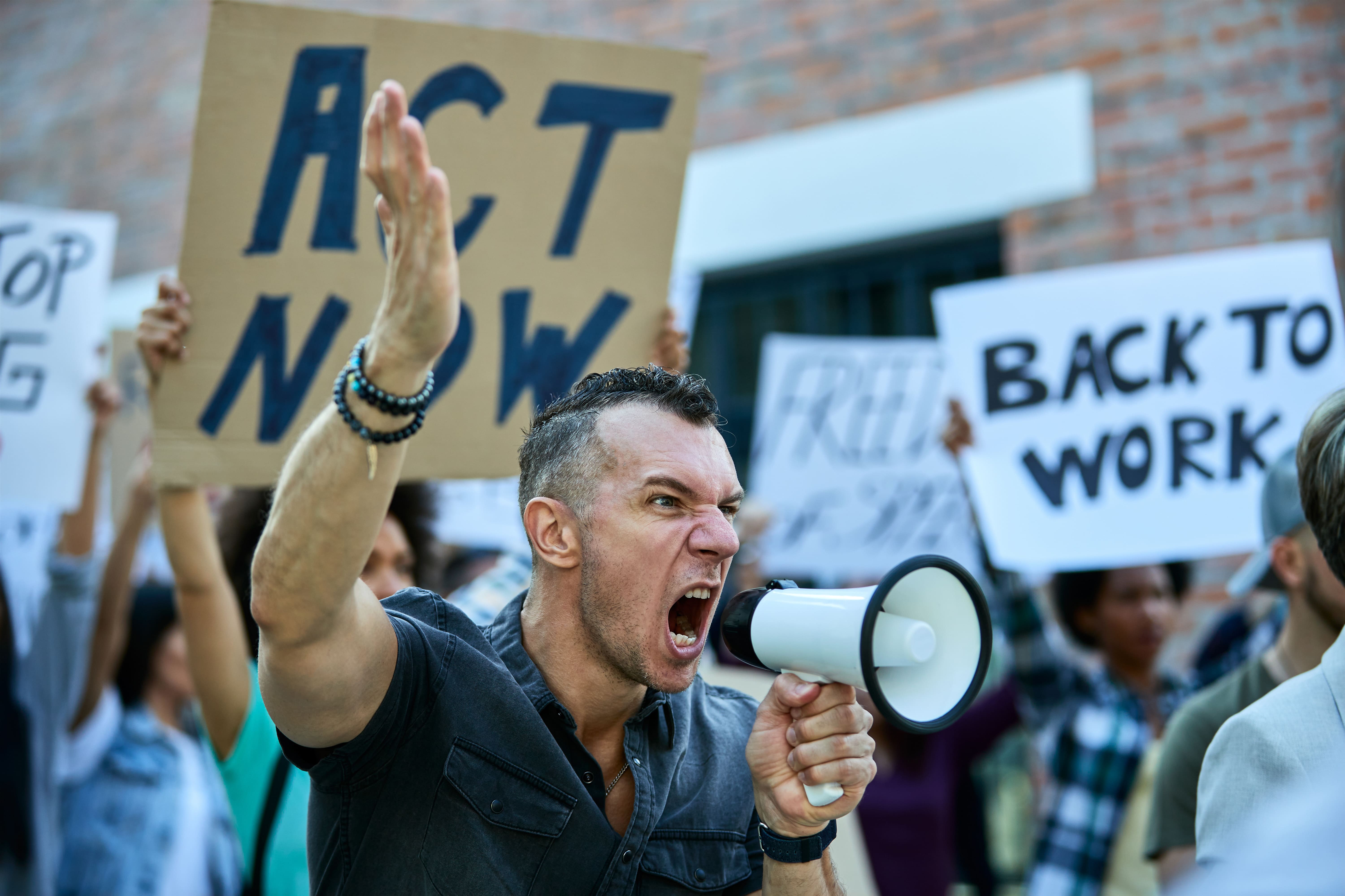 angry-protester-using-megaphone-shouting-while-protesting-with-crowd-people-city-streets