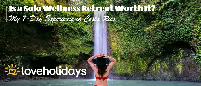 Woman in a red swimsuit standing under a lush green waterfall in Costa Rica with text overlay reading “Is a Solo Wellness Retreat Worth It? My 7-Day Experience in Costa Rica” and Loveholidays logo.