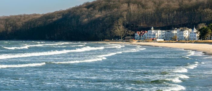 A scenic beach with gentle waves lapping at the shore, lined with charming houses in the background.